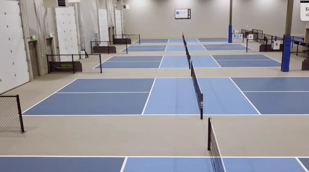 An indoor Sinclair tennis court with blue and white lines.